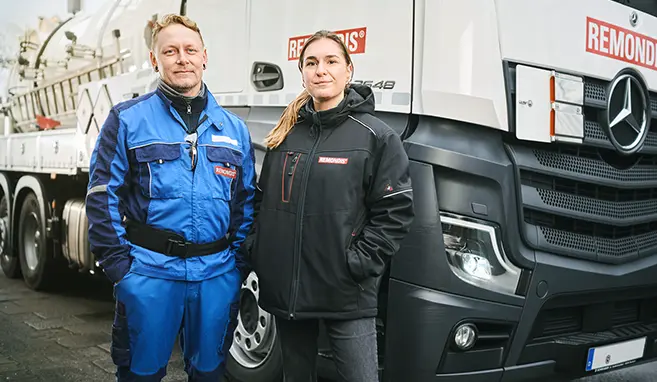 Zwei Mitarbeitende von REMONDIS (ein Mann und eine Frau) stehen vor einem Saug-Druck-Tankfahrzeug und schauen in die Kamera.