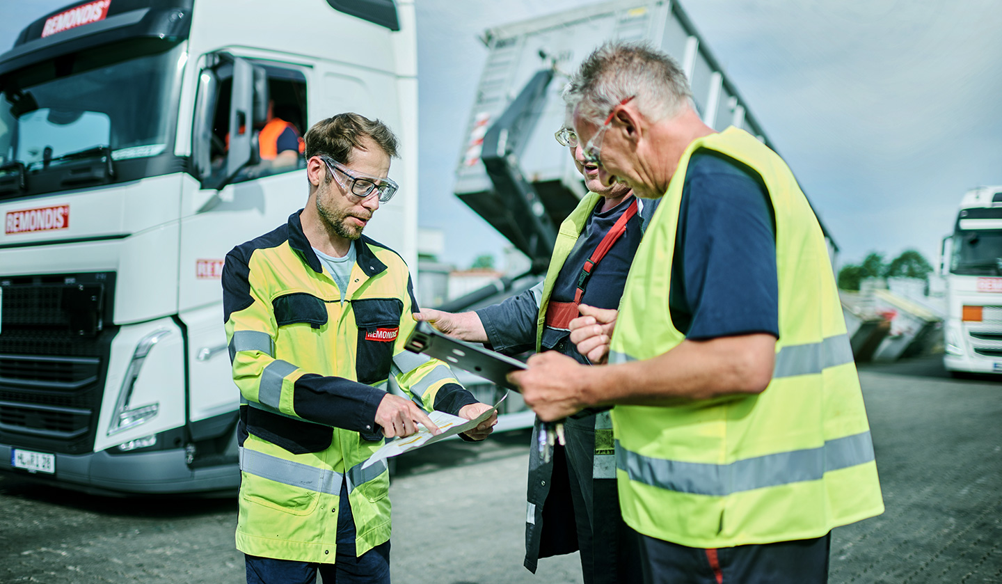 A waste management officer talking with two employees